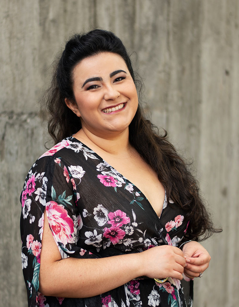 Susana in a floral dress, smiling at the camera